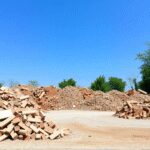 Des piles de déchets de construction soigneusement rangées, comme du béton, des briques et des carreaux, sur un site propre entouré d'arbres verts ...
